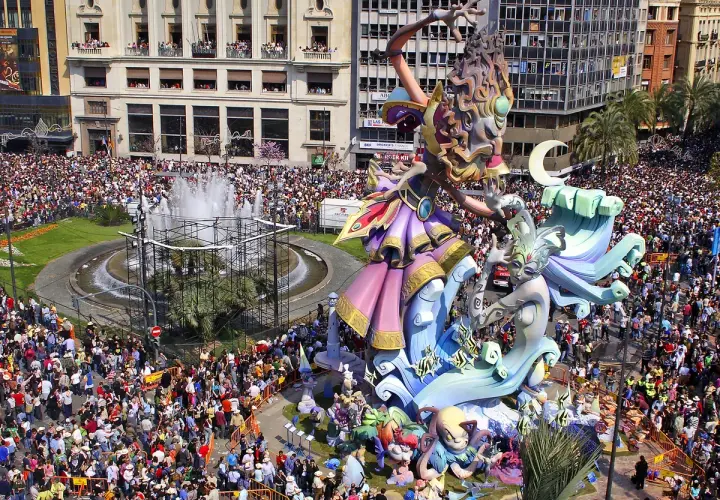 Gigantescas figuras de las mejores Fallas de Valencia, rodeadas de miles de personas, celebran la fiesta en una plaza con fuente.