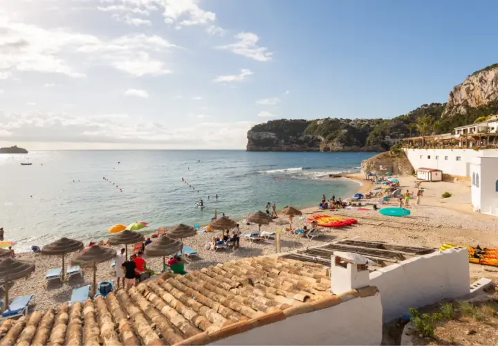 La cala Barraca, con su playa de guijarros, aguas cristalinas y acantilados, es un paraíso para disfrutar del sol y el mar. Kayaks y sombrillas invitan al descanso.