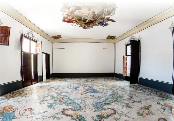 Interior de un museo de la seda con suelo de azulejos pintados y frescos en el techo.