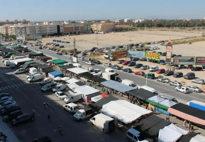 Vista aérea de un bullicioso mercadillo en Elche, con puestos, furgonetas y coches aparcados.