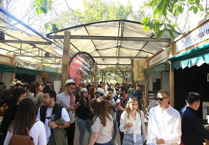 Gente disfrutando en la feria del vino Valencia, con puestos de degustación y ambiente festivo bajo toldos.