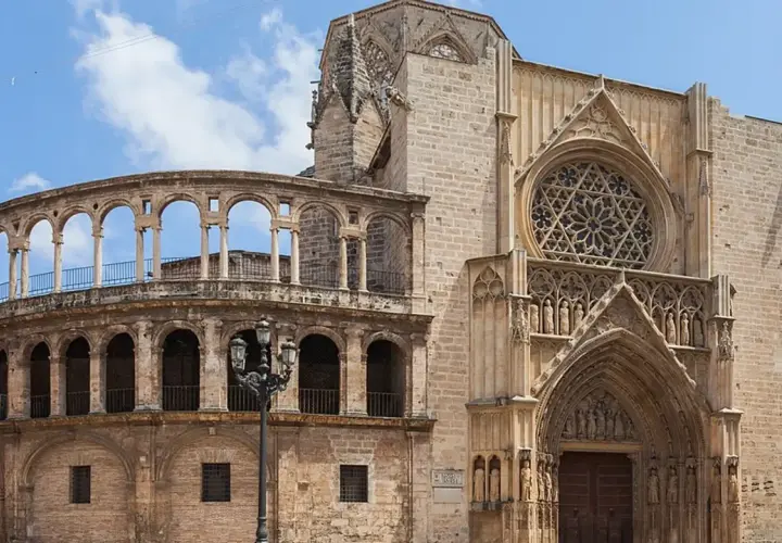 La **catedral de Valencia** luce su fachada gótica con un rosetón y un pórtico detallado, junto a una estructura de arcos semicirculares.