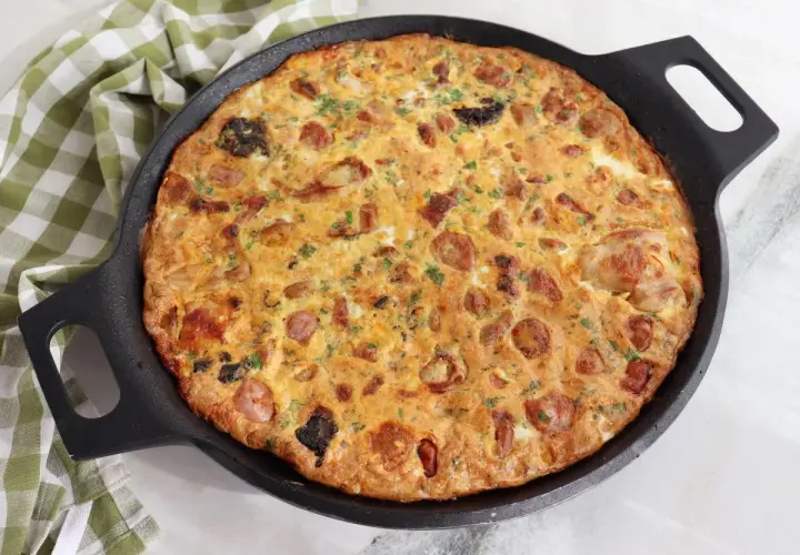 Arroz con costra de Elche recién hecho en sartén, con trozos de salchicha y perejil picado.