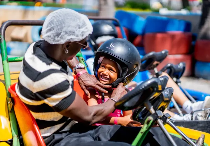 Un padre ajusta el casco a su hija en un kart en el Santa Pola Park. Ambos sonríen, listos para la carrera.