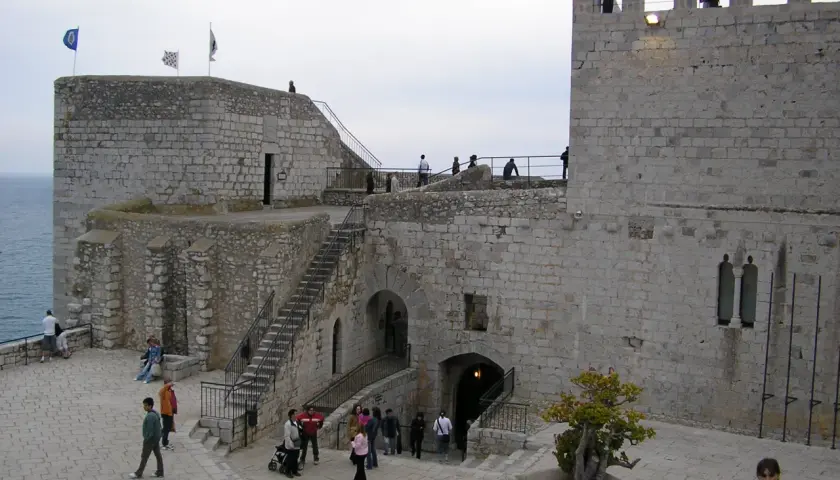 El castillo del Papa Luna en Peñíscola, con sus murallas de piedra y escalinatas, recibe a visitantes que pasean por sus patios.