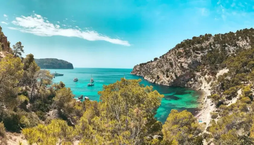 Unas calas de ensueño en la Costa Blanca, con aguas turquesas, vegetación exuberante y barcos navegando.