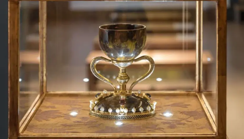 Cáliz dorado con asas, adornado con perlas y gemas, exhibido en vitrina. ¿Será este donde está el santo grial?