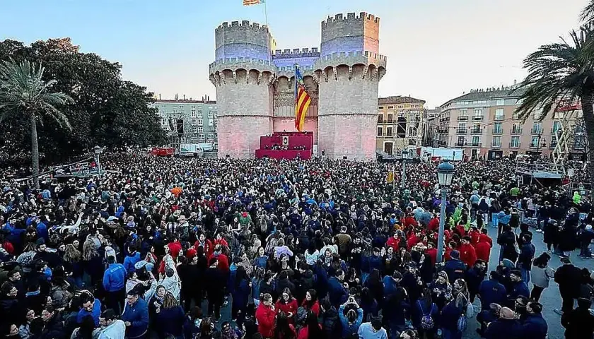 Multitudinaria **la crida valencia** ante las Torres de Serranos, con banderas valencianas ondeando y un escenario preparado.