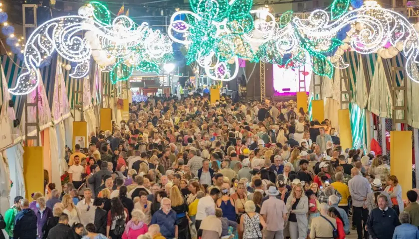 Multitudinaria feria nocturna con arcos de luces y puestos.