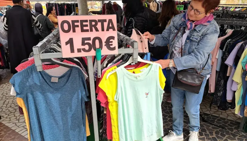 En el mercadillo de Gandía, una mujer busca ofertas. Ropa a 1,50€ en un puesto.