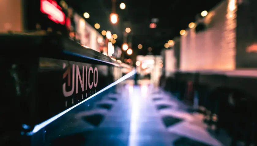 El logo "ÚNICO VALENCIA" brilla en la barra de un local, invitando a disfrutar del tardeo.