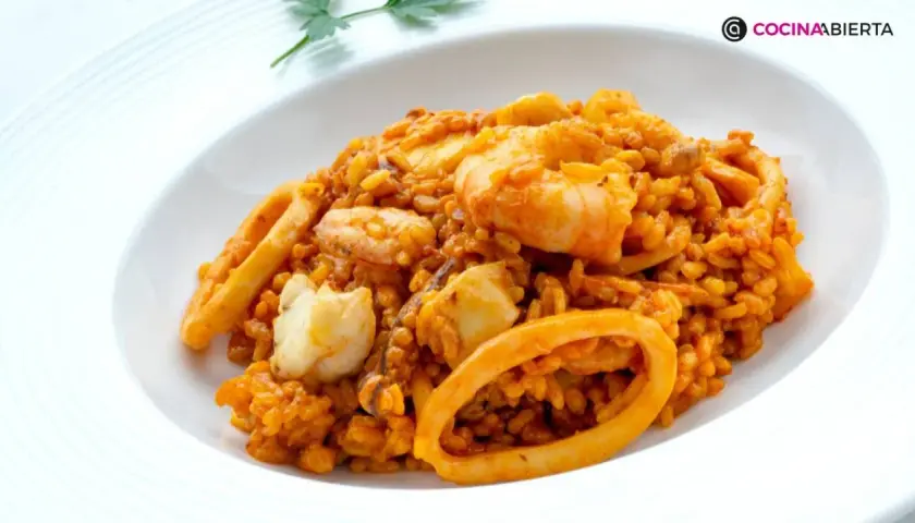 Arroz del senyoret con gambas, calamares y trozos de pescado blanco, servido en un plato blanco.