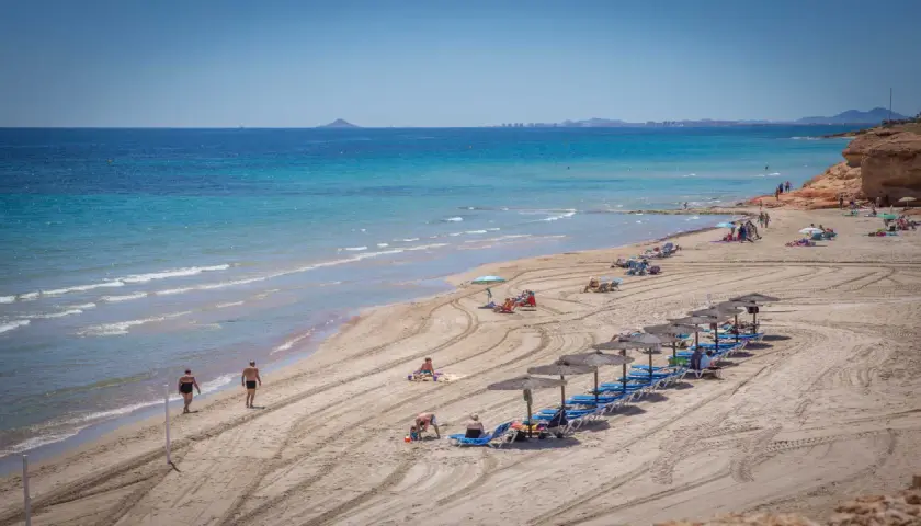 Una hermosa playa de mil palmeras con gente disfrutando del sol y el mar turquesa.
