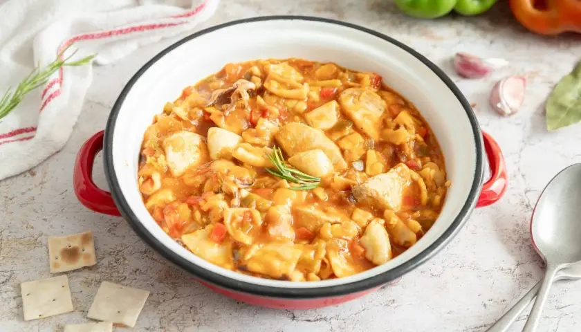Gazpacho de mero Santa Pola, un plato marinero con trozos de pescado, pimientos y tomate en una cazuela roja.