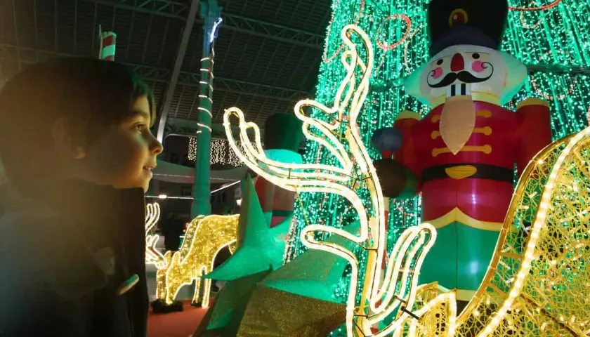 Niño mira con asombro el encendido de luces de Navidad en Valencia, con un cascanueces gigante y renos luminosos.
