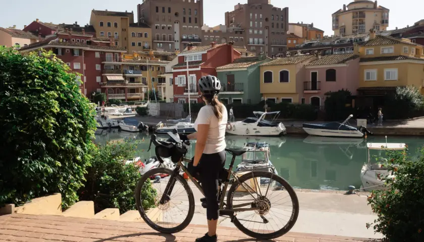 Ciclista en Valencia, disfrutando de las rutas ciclistas junto a un canal con casas coloridas y barcos.