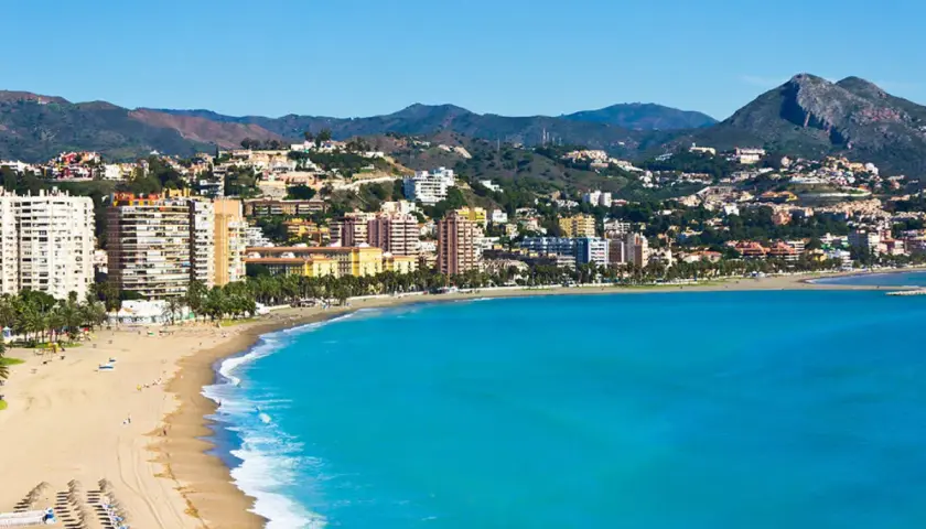 Vista panorámica de zonas de Alicante con playa, edificios altos y montañas al fondo.