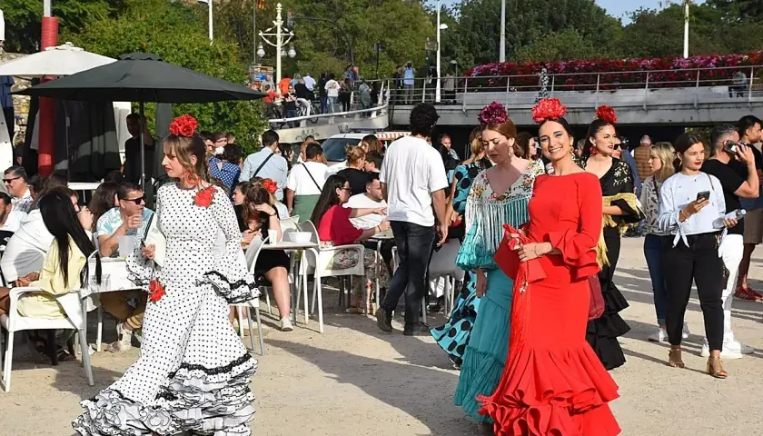 Mujeres con trajes de flamenca en la feria de abril de Valencia. Ambiente festivo con gente disfrutando.