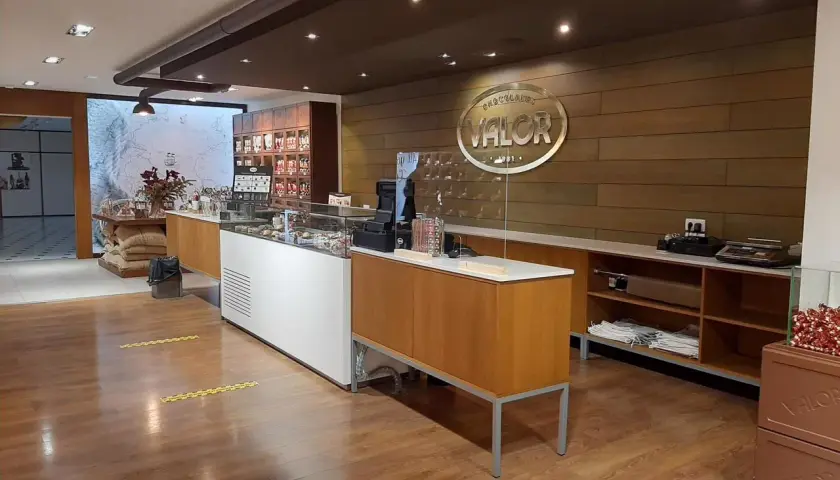 Interior de una tienda de chocolates Valor, con vitrinas, estanterías y el logo de la fábrica.