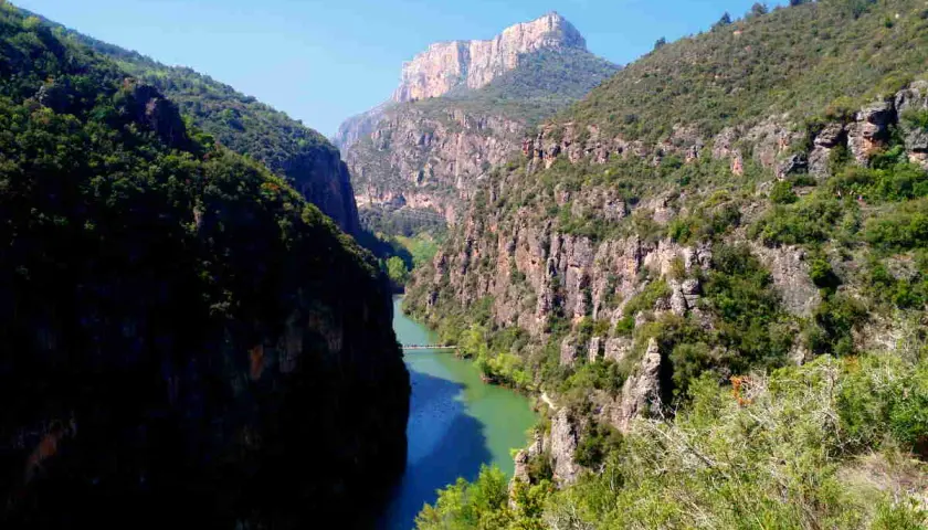 Impresionante desfiladero de Mont-rebei, con un río de aguas turquesas serpenteando entre imponentes paredes rocosas cubiertas de vegetación.