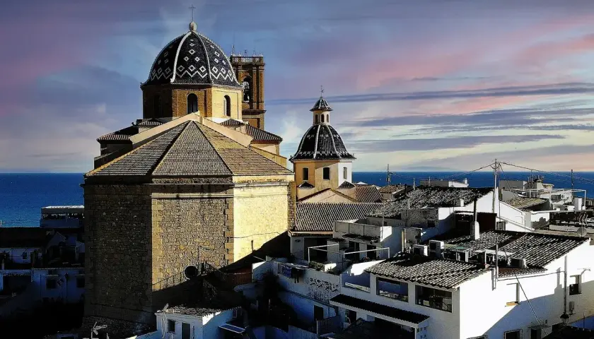 Altea vieille ville, con sus cúpulas y tejados blancos, se asoma al mar Mediterráneo bajo un cielo teñido de rosa y azul.