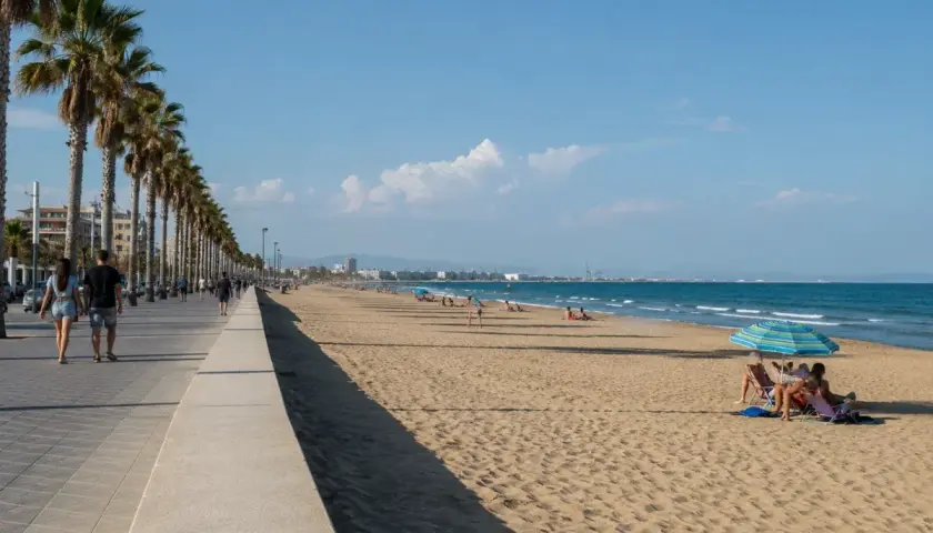 Paseo marítimo con palmeras y gente disfrutando de las **plages valence** bajo un cielo azul.