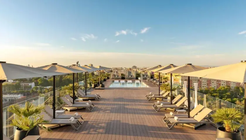 Terraza con piscina y tumbonas en el Novotel Valencia, vistas a la ciudad al atardecer.