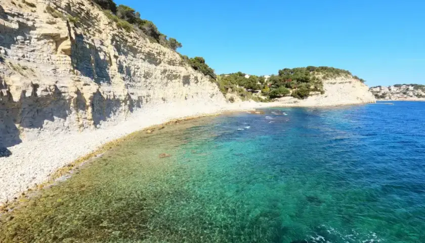 Aguas cristalinas y acantilados en la cala llobella, un paraíso mediterráneo.