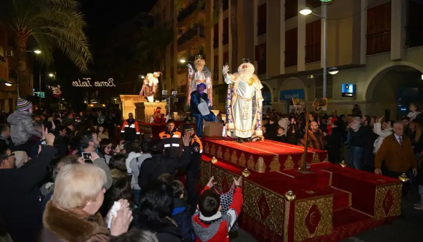 La cabalgata de Reyes en Valencia ilumina la noche con sus majestuosas carrozas y la multitud expectante. Melchor, Gaspar y Baltasar saludan a los niños.