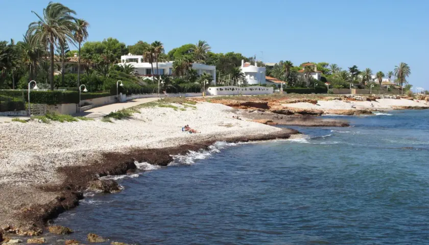Un paseo junto a las mejores calas de Dénia, con casas blancas, palmeras y el mar azul.