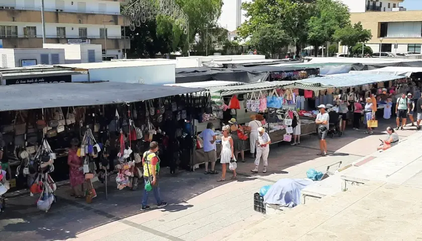 Gente paseando y comprando en el mercadillo de Jávea, con puestos de bolsos y ropa bajo toldos.