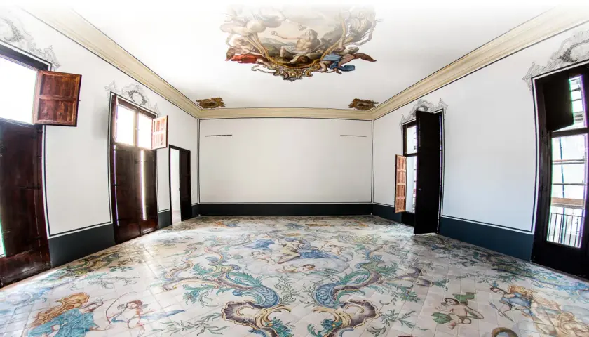Interior de un museo de la seda con suelo de azulejos pintados y frescos en el techo.