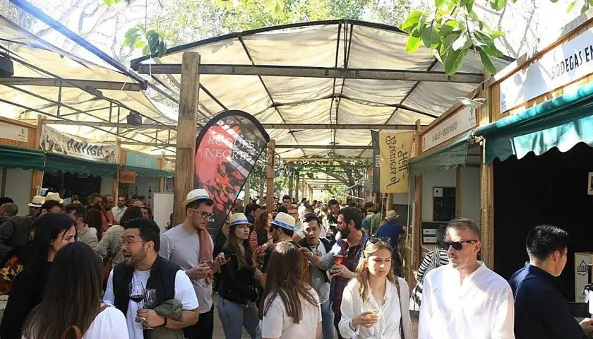 Gente disfrutando en la feria del vino Valencia, con puestos de degustación y ambiente festivo bajo toldos.
