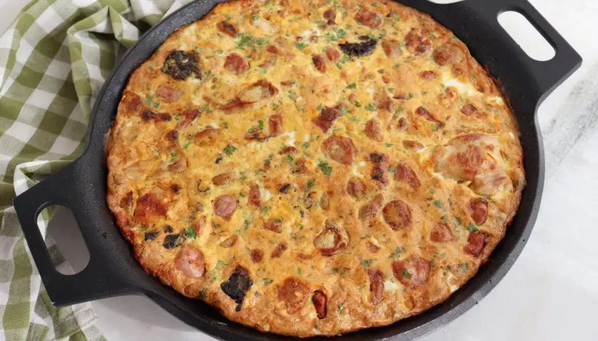 Arroz con costra de Elche recién hecho en sartén, con trozos de salchicha y perejil picado.