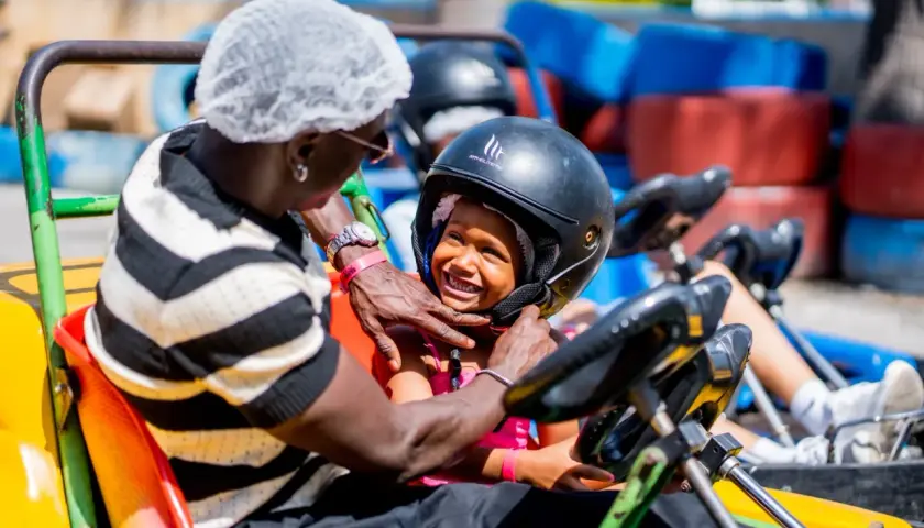 Un padre ajusta el casco a su hija en un kart en el Santa Pola Park. Ambos sonríen, listos para la carrera.