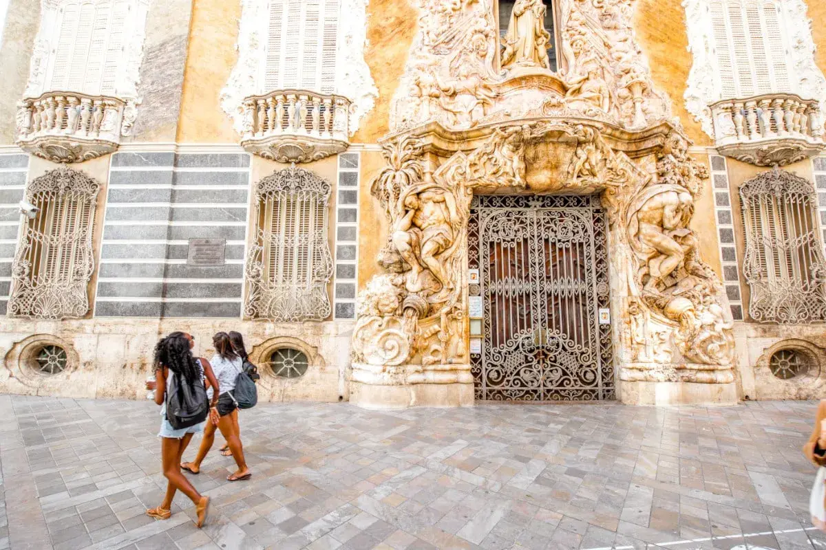 Dos chicas pasean frente a un edificio ornamentado, buscando museos gratis en Valencia.