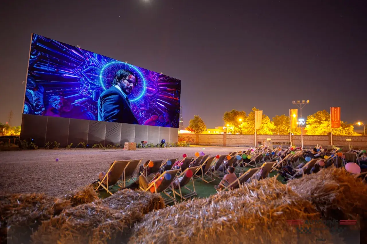 Noche de cine al aire libre en Valencia. Gente relajada en tumbonas viendo una película en pantalla gigante.
