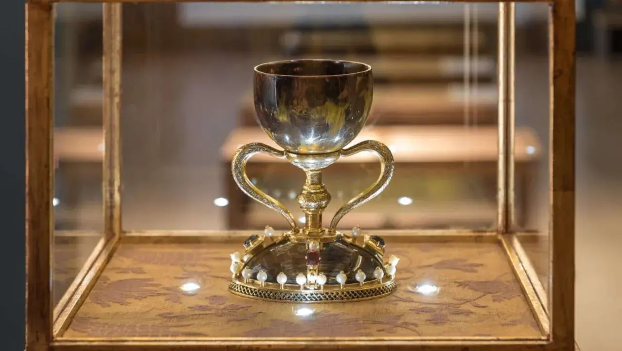 Cáliz dorado con asas, adornado con perlas y gemas, exhibido en vitrina. ¿Será este donde está el santo grial?