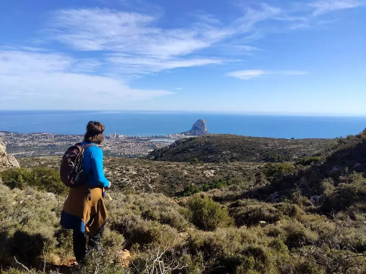 Senderista contempla el Peñón de Ifach y la costa desde una de las rutas de Calpe.