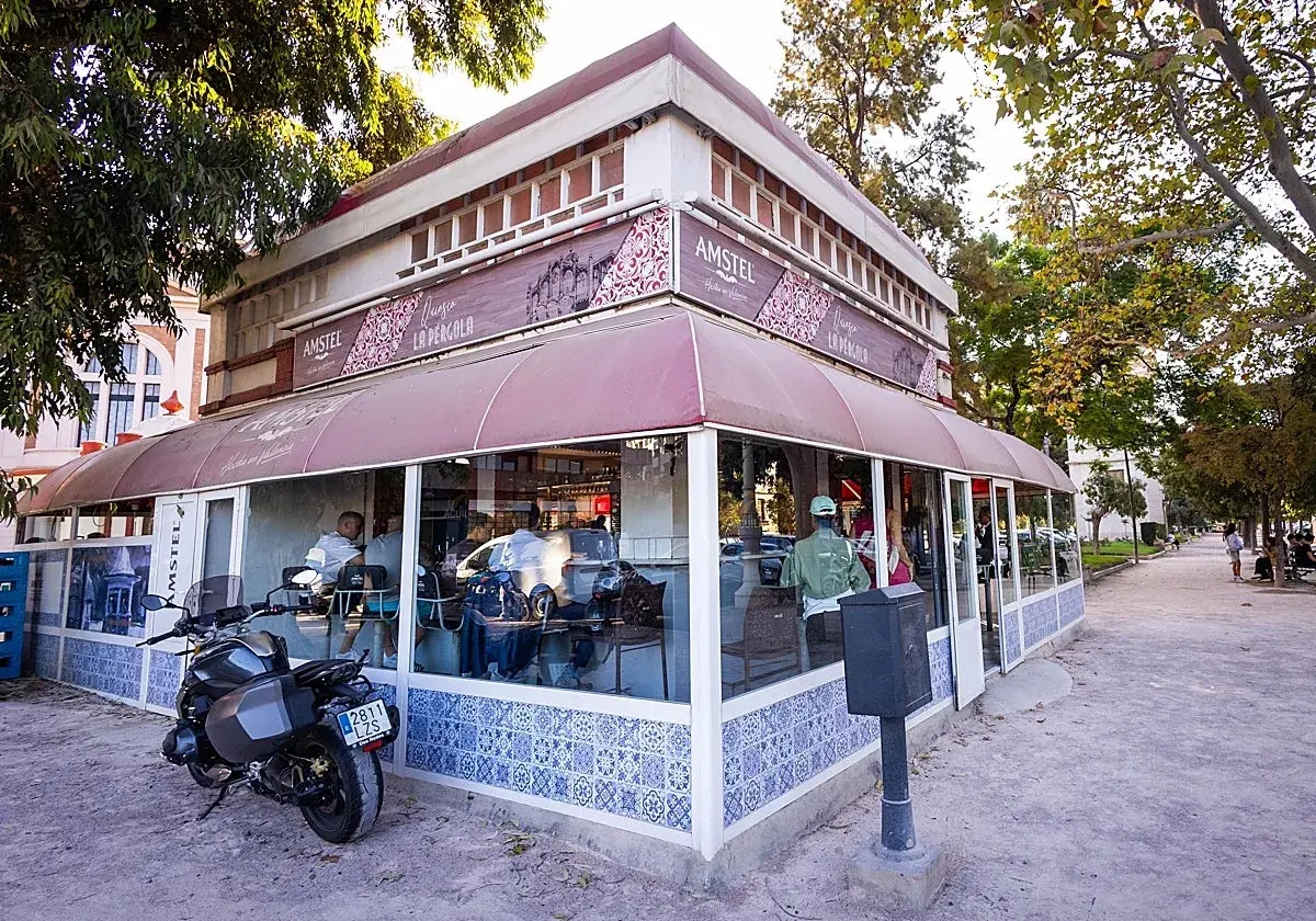 La pergola Valencia, un café con terraza y moto aparcada, invita a disfrutar del día.