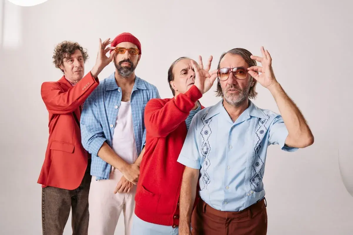 Cuarteto de Nos en Valencia, con gafas de sol y atuendos coloridos, listos para un concierto.