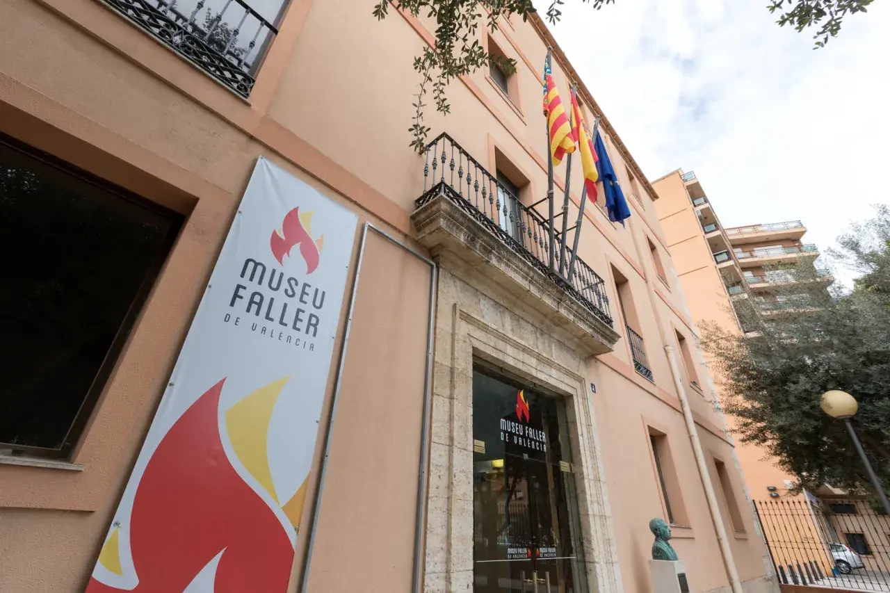 Fachada del Museu Faller de València con un cartel anunciador y banderas ondeando.