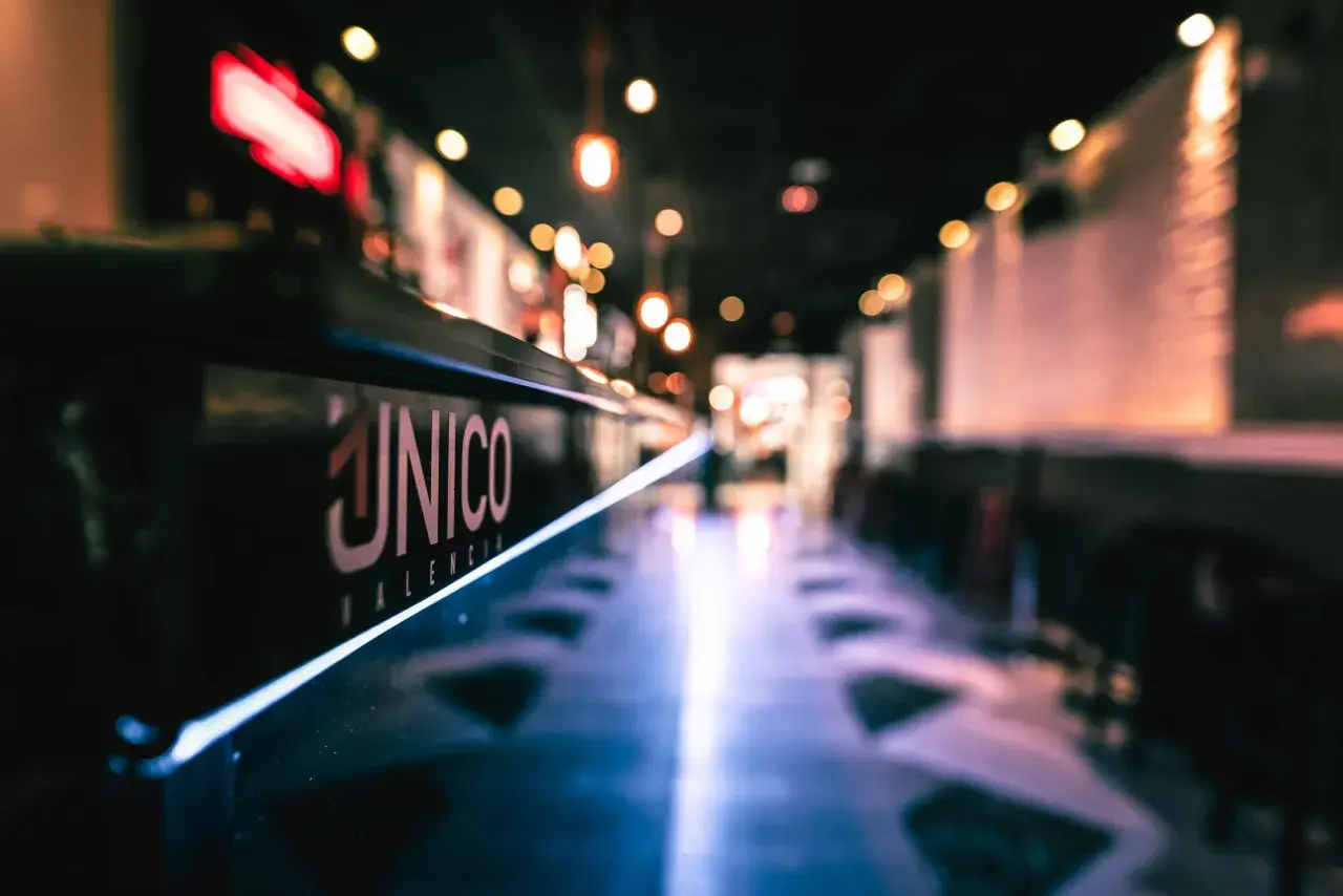 El logo "ÚNICO VALENCIA" brilla en la barra de un local, invitando a disfrutar del tardeo.