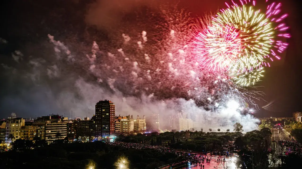 Espectacular noche de fuegos artificiales ilumina el cielo de Valencia. Multitudes observan la fiesta desde las calles.