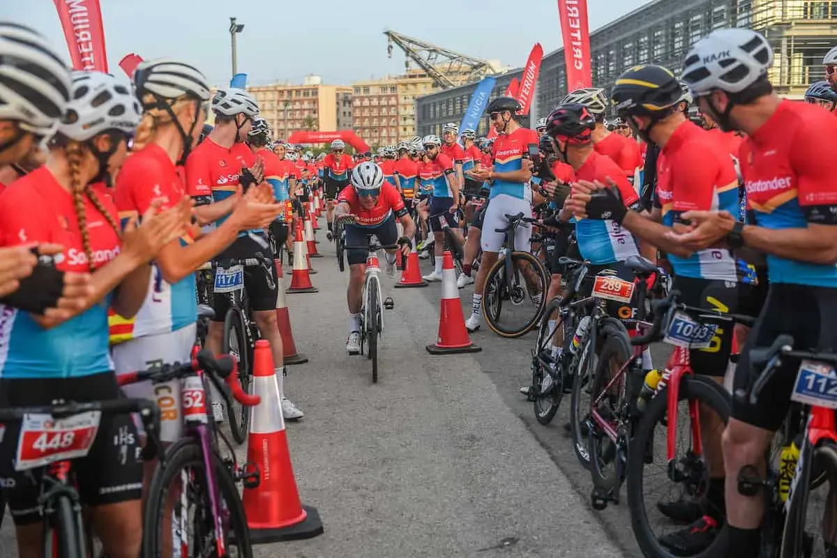 Ciclistas compiten en un gran fondo en Valencia. El público anima a los participantes mientras uno cruza la meta.
