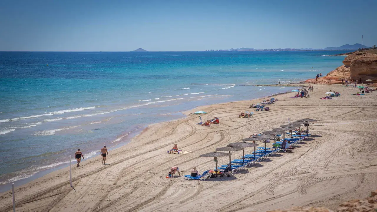 Una hermosa playa de mil palmeras con gente disfrutando del sol y el mar turquesa.