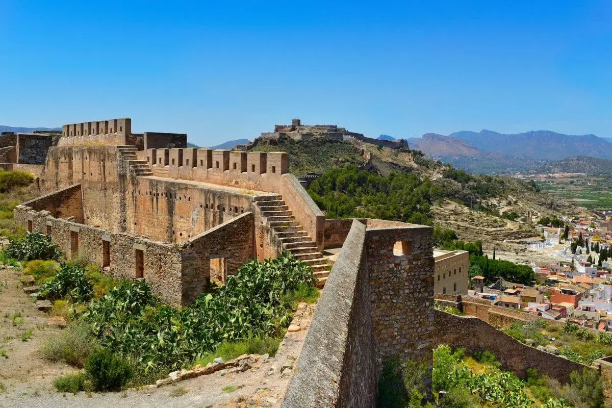 Ruinas del castillo de Sagunto, con sus imponentes murallas de piedra y escalinatas, dominan el paisaje montañoso.