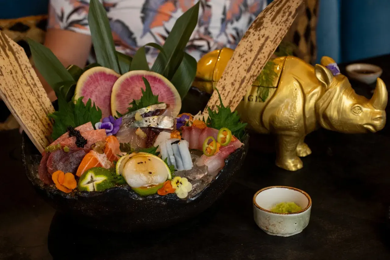 Un festín de sashimi en uno de los restaurantes temáticos de Valencia, con un rinoceronte dorado de decoración.