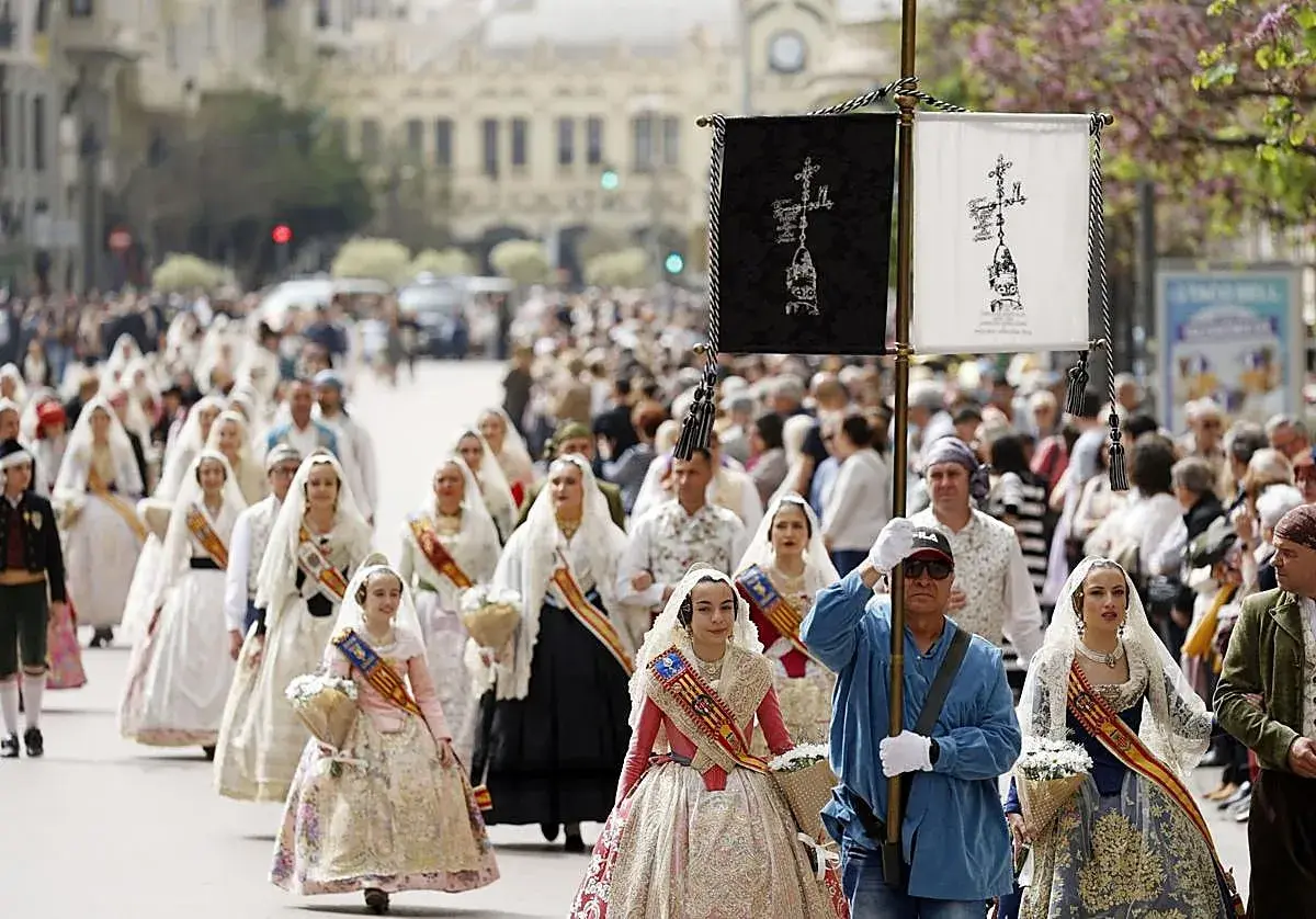 Procesión de mujeres con trajes tradicionales valencianos, celebrando cuando es San Vicente en Valencia.