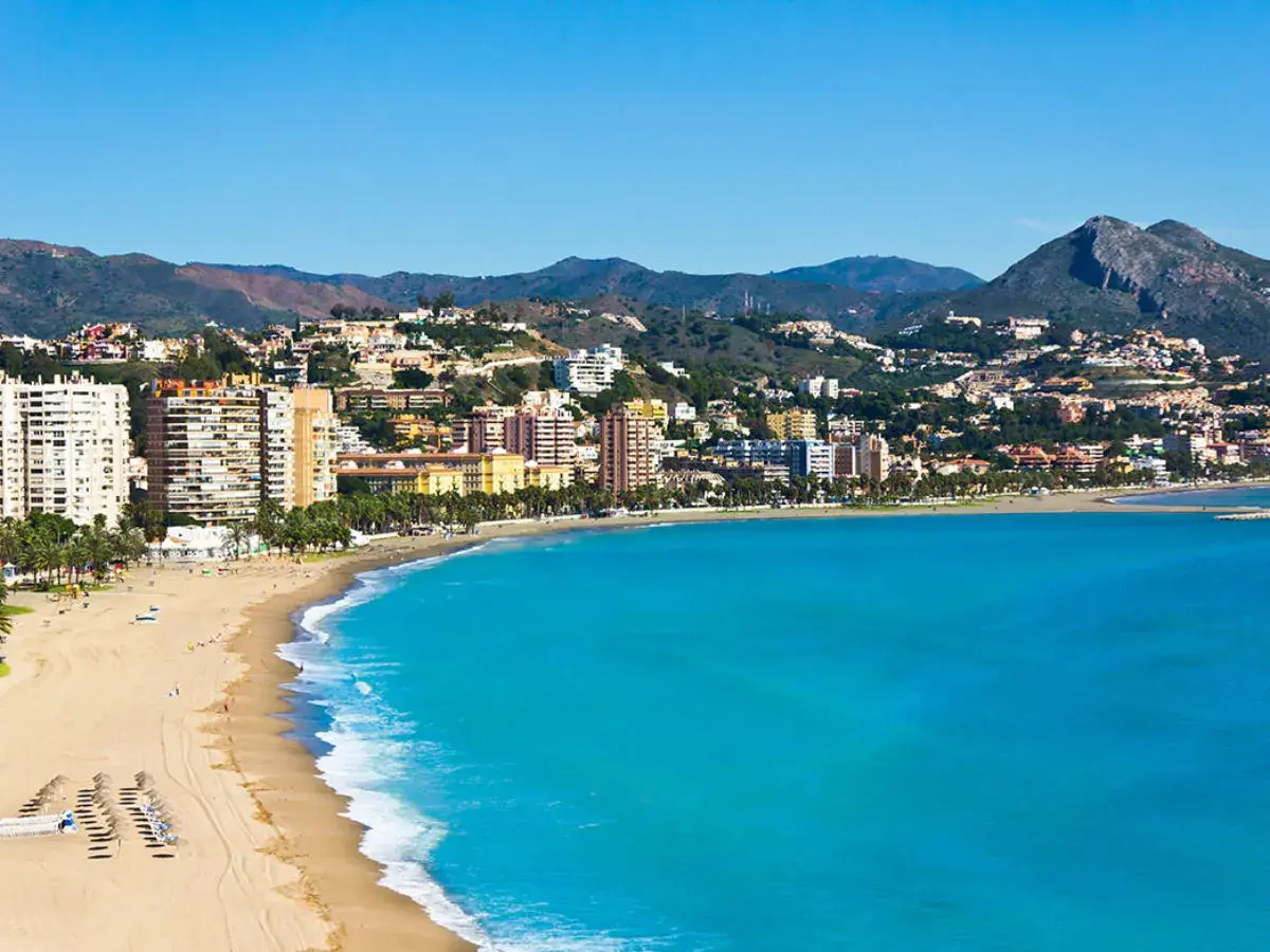 Vista panorámica de zonas de Alicante con playa, edificios altos y montañas al fondo.